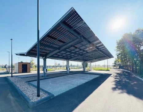 Parc solaire en pleine campagne sous ciel bleu nuageux avec soleil &eacute;clatant