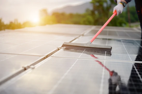 Ext&eacute;rieur, technicien avec gants noirs nettoie panneau solaire photovolta&iuml;que avec jet d'eau haute pression