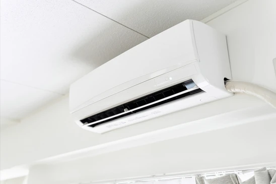 Technicien installant une unit&eacute; ext&eacute;rieure de climatisation sur fa&ccedil;ade en briques