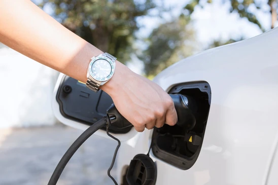 Sc&egrave;ne ext&eacute;rieure urbaine avec v&eacute;hicule &eacute;lectrique blanc en charge sur borne publique