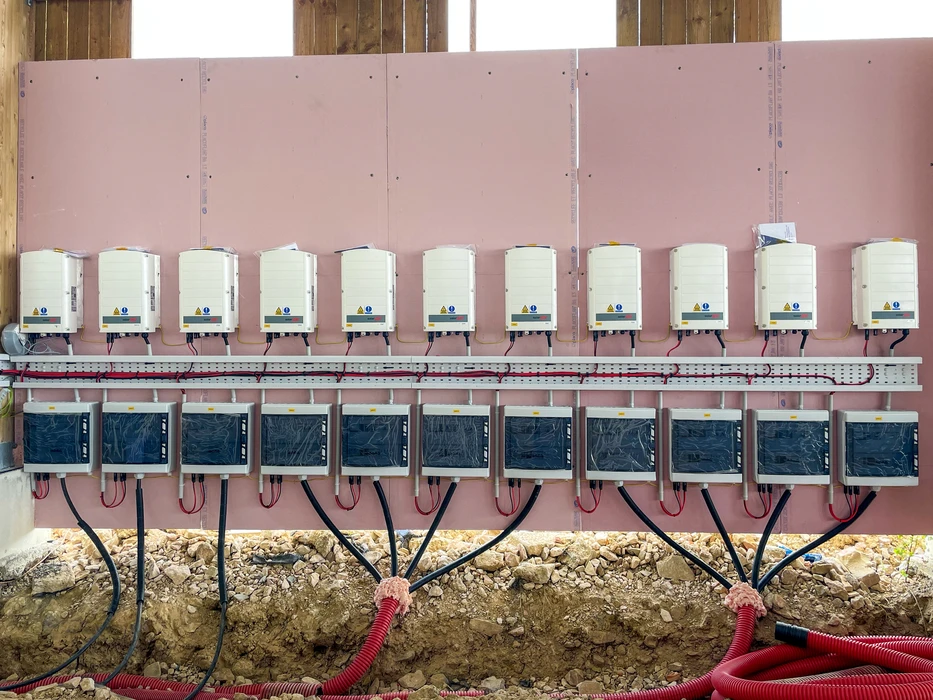 Deux techniciens en équipements de protection individuelle inspectent une installation solaire photovoltaïque sous un ciel nuageux