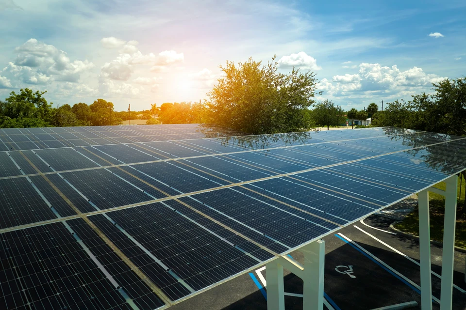 Station de recharge électrique extérieure avec trois véhicules électriques stationnés sous un auvent équipé de panneaux solaires photovoltaïques