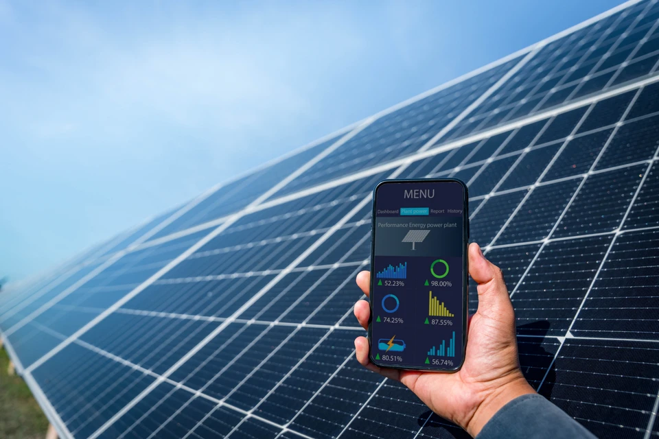 Technicien en gilet haute visibilité jaune utilisant une tablette numérique pour contrôler une installation de panneaux solaires photovoltaïques