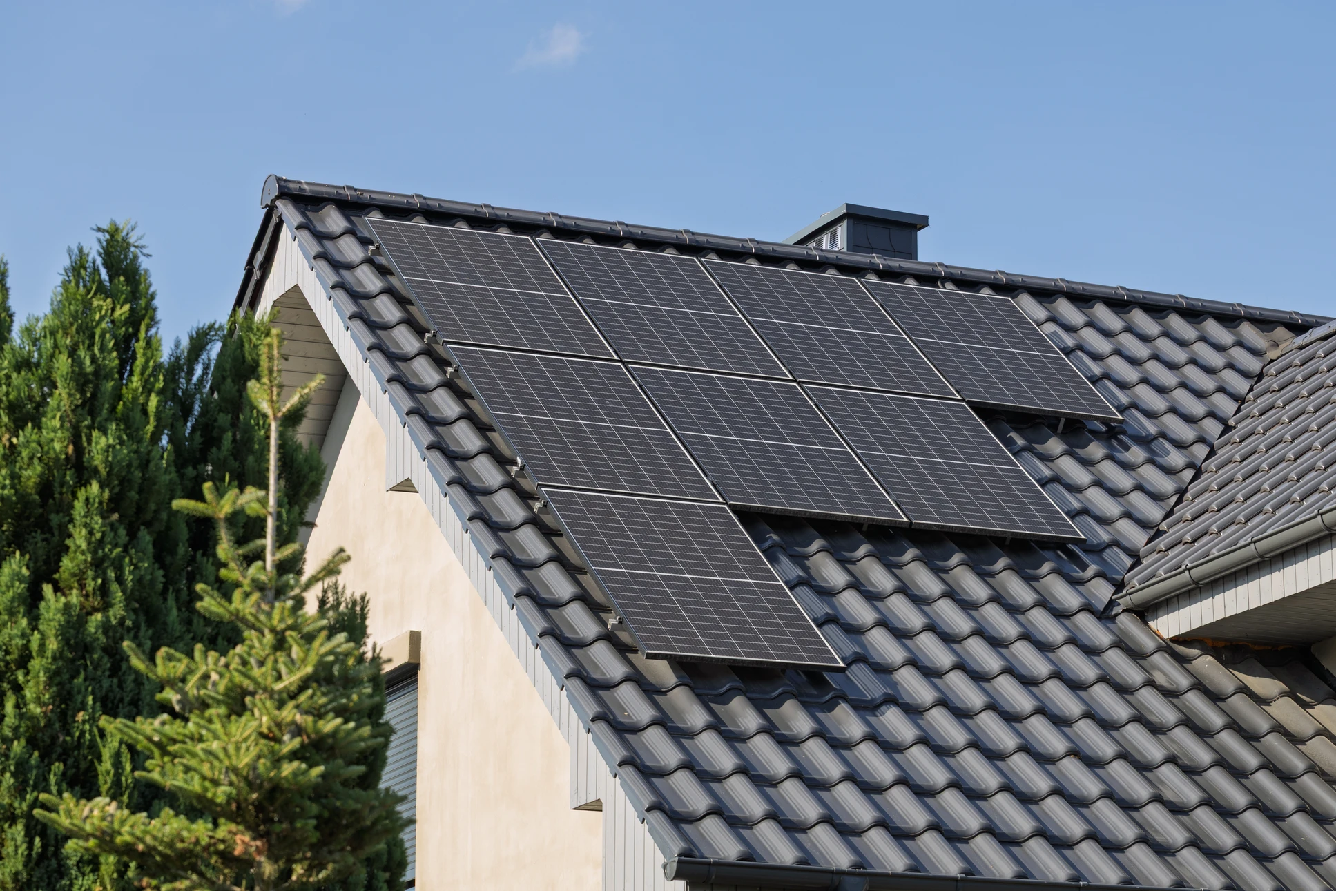 Deux techniciens travaillent sur une toiture terrasse métallique au coucher du soleil, ville en arrière-plan