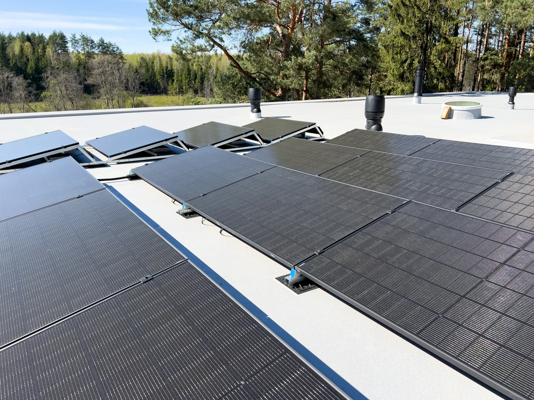 Deux techniciens travaillent sur une toiture terrasse métallique au coucher du soleil, ville en arrière-plan