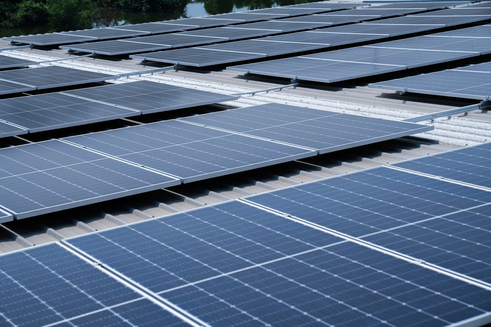 Installation photovoltaïque professionnelle de grande envergure sur toiture industrielle ou commerciale : plusieurs rangées de panneaux solaires disposés en parallèle sur une vaste toiture plate de bâtiment commercial ou usine, vue aérienne ou en contre-plongée mettant en évidence l'ampleur du projet. La scène doit montrer clairement un contexte B2B d'envergure, avec des panneaux couvrant une superficie importante, sans présence de personnes visibles.